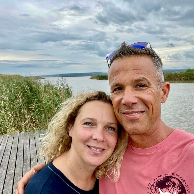 Frau und Mann umarmen sich, im Hintergrund ein See mit Schilfgürtel