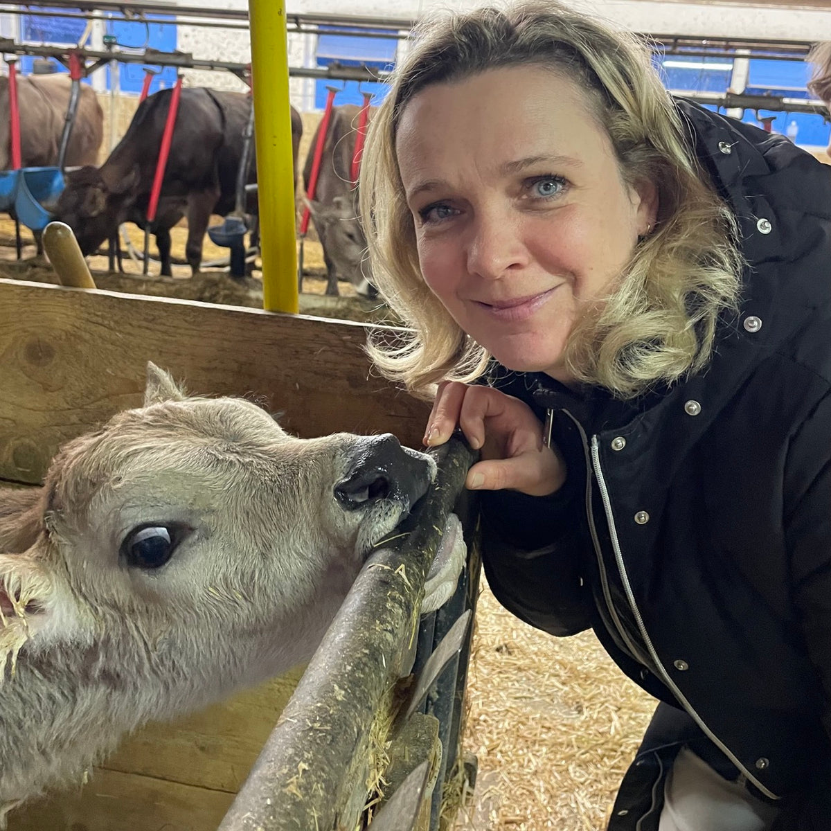 Frau steht neben einem Kalb, sieht in die Kamera
