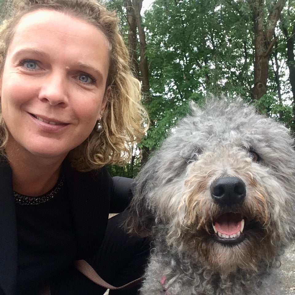 Portrait einer Frau, die neben einem grauen langhaarigen Hund hockt