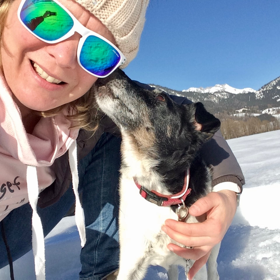 Kleiner Hund schnüffelt zum Gesicht einer Frau, die neben ihm sitzt, Winterstimmung